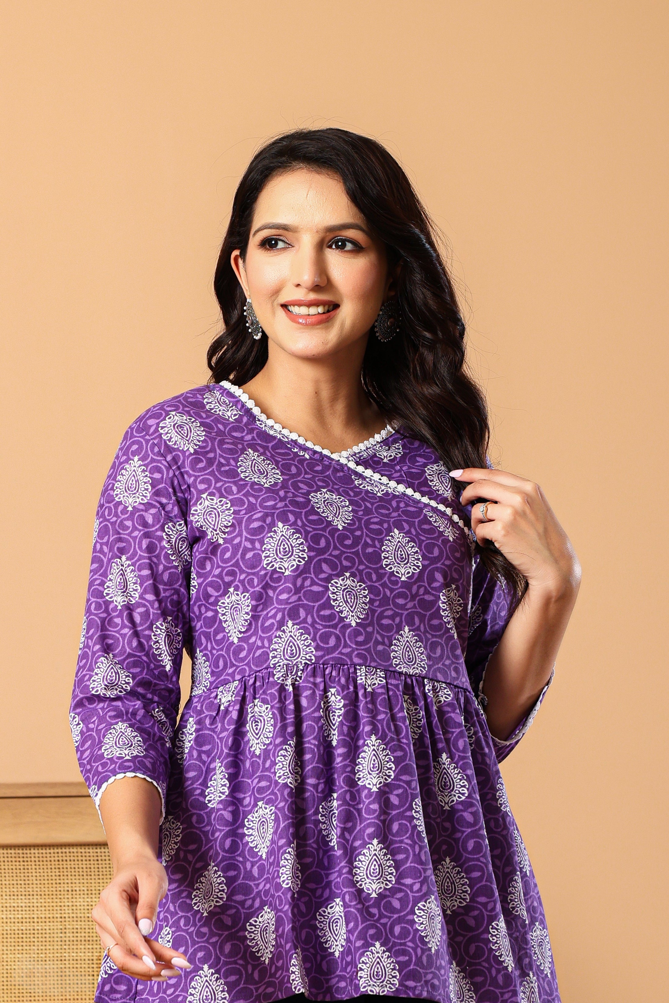 Woman wearing a purple patterned top against a beige background